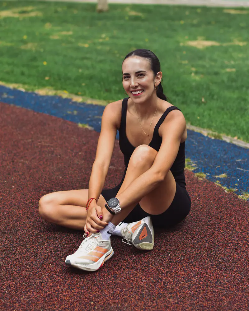 Ivanna sentada en la pista, sonriendo a la cámara después de entrenar.