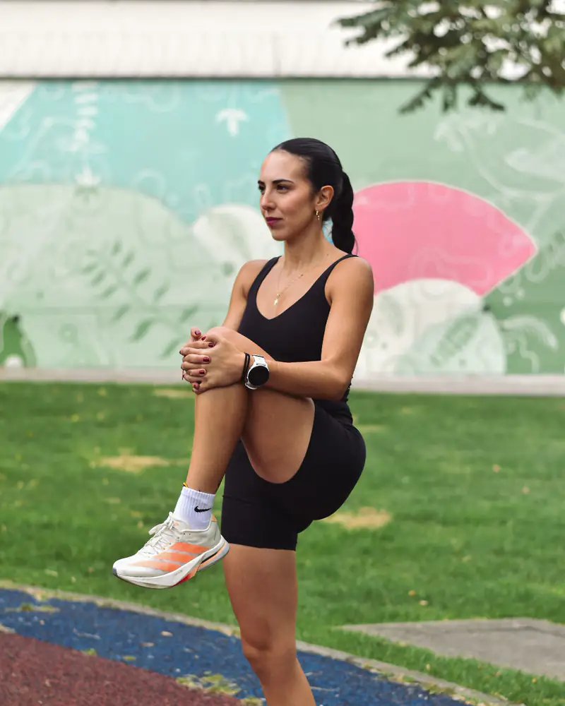 Ivanna calentando de pie, con una rodilla recogida contra el pecho.